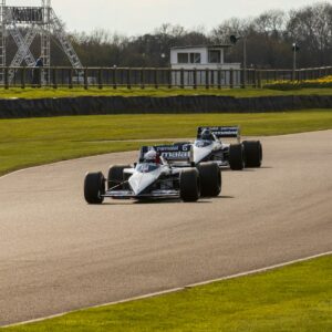 a couple of racing cars driving down a race track